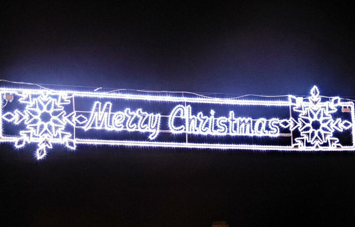 Decorative LED sign with 'Merry Christmas' text and snowflake designs on a dark background.